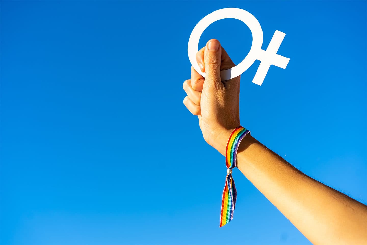 Blue sky background with a hand of a woman with female symbol in favor of feminism